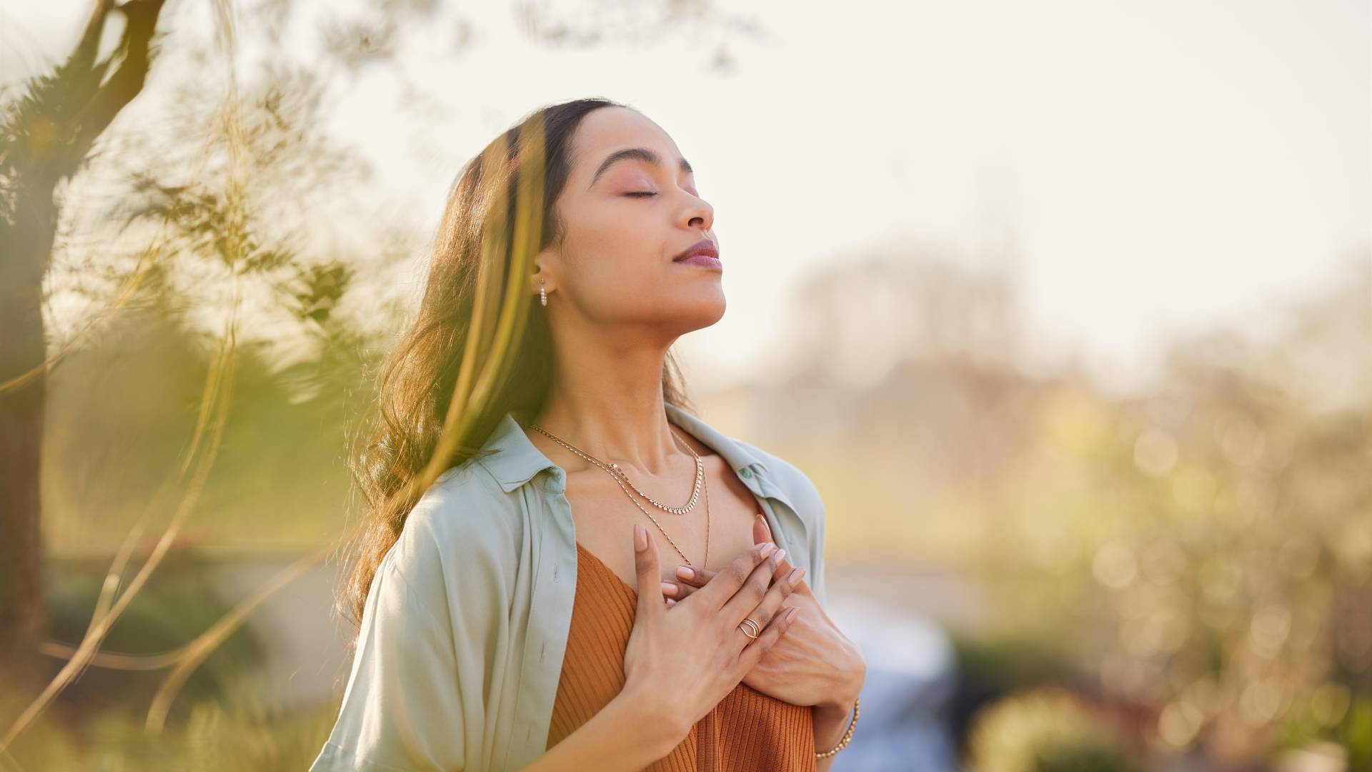 Woman takes a deep breath in the fresh air and touches her heart
