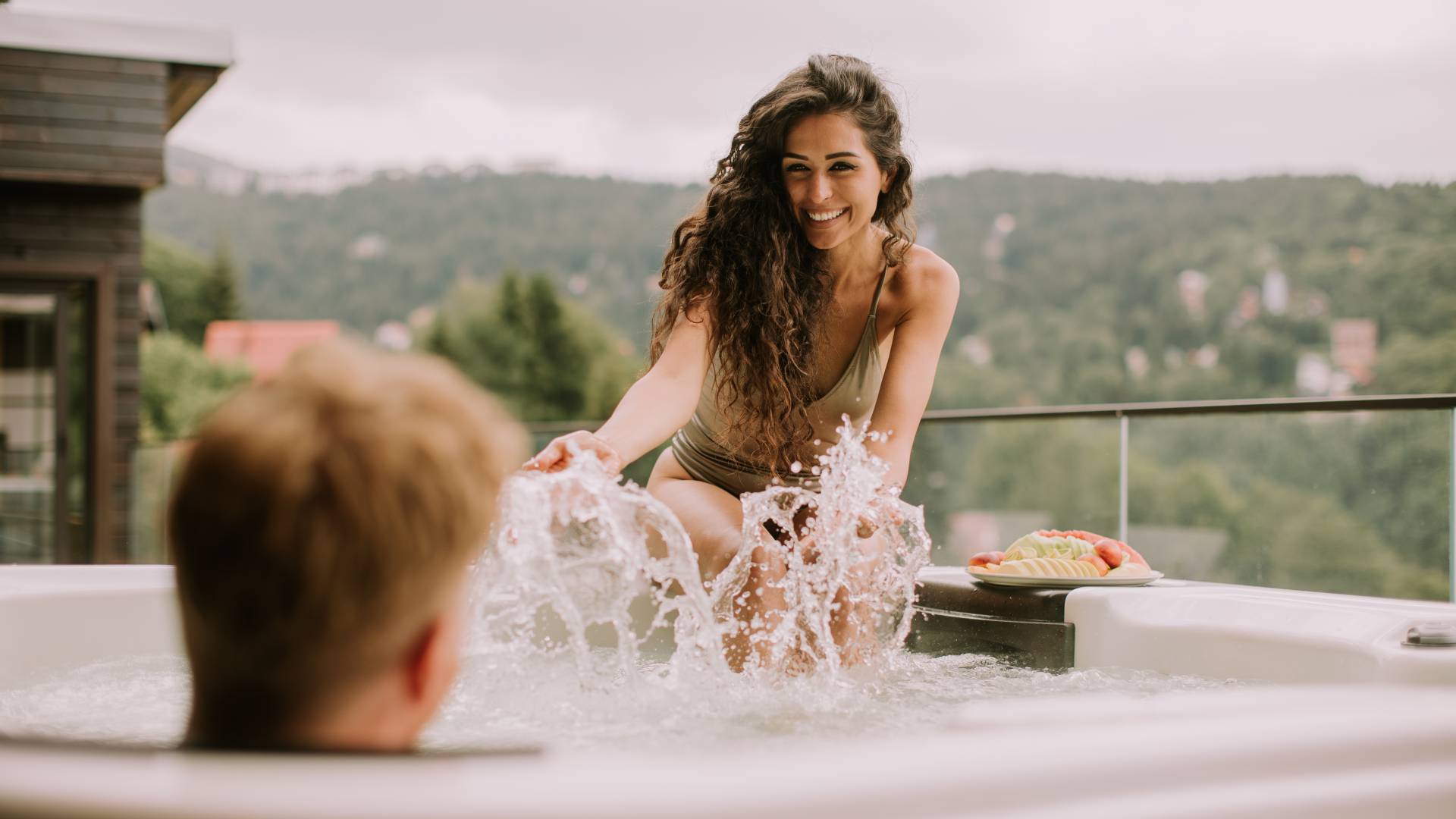 Young couple relaxing in hot tub with fruit platter on vacation
