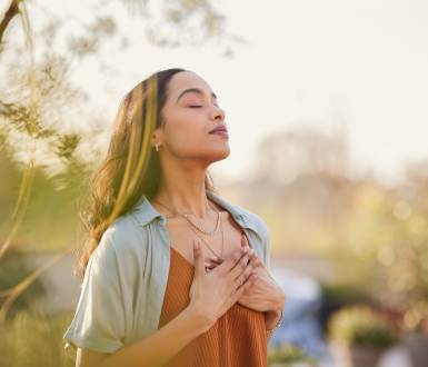 Woman takes a deep breath in the fresh air and touches her heart
