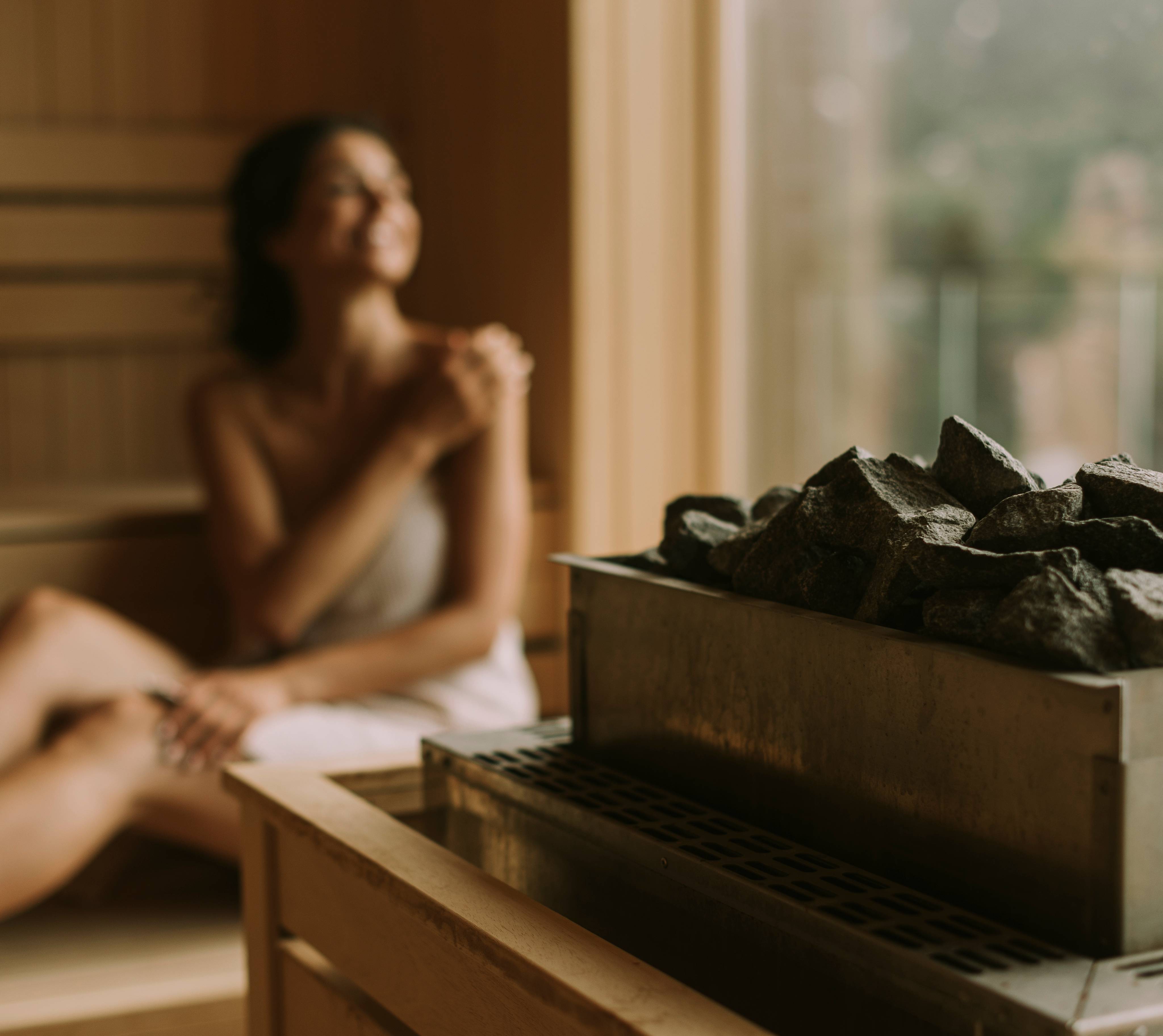 Junge Frau sitzt in der Sauna und geniesst die Aussicht