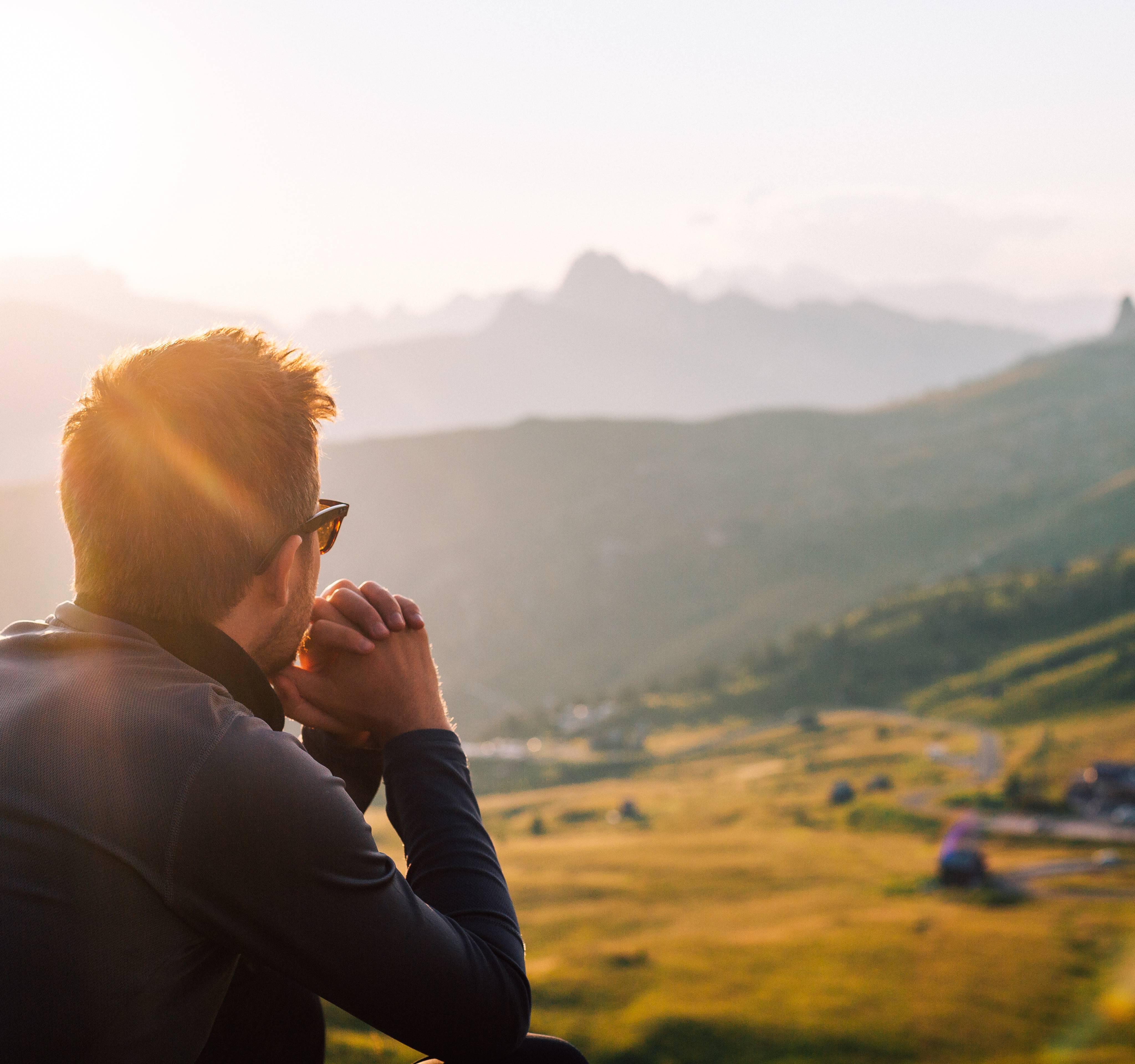 Mann mit Sonnenbrille in den Bergen und geniesst die Natur