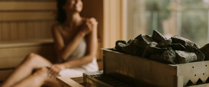 Junge Frau sitzt in der Sauna und geniesst die Aussicht