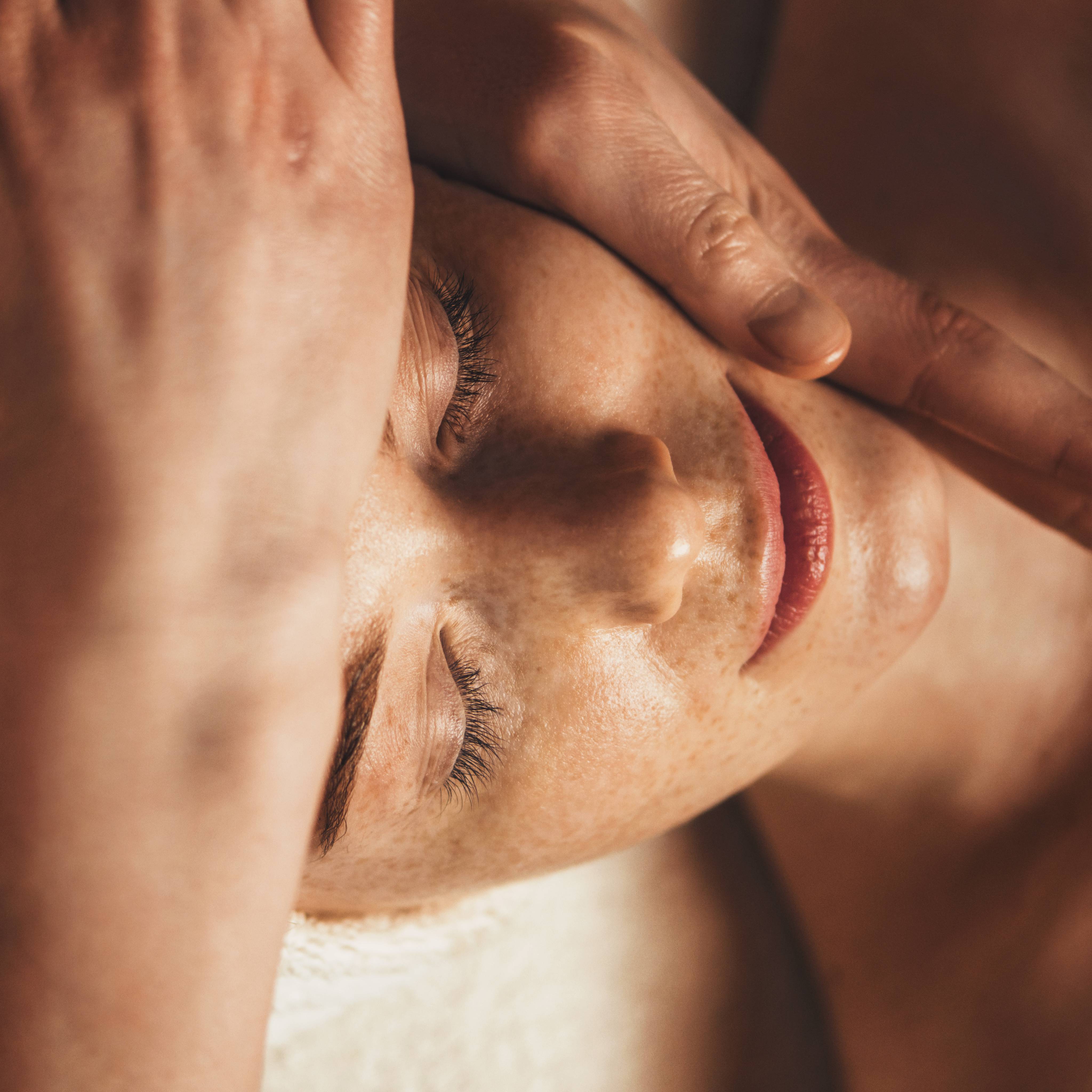 Schöne sommersprossige Frau bekommt eine Gesichtsmassage im Schönheitssalon.